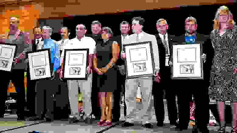 Large Group of People Proudly Displaying Award Plaques on a Stage